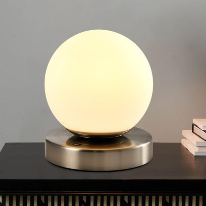Tischlampe mit kugelförmigem Opalglas und warmweißem Licht auf runder Metallbasis
