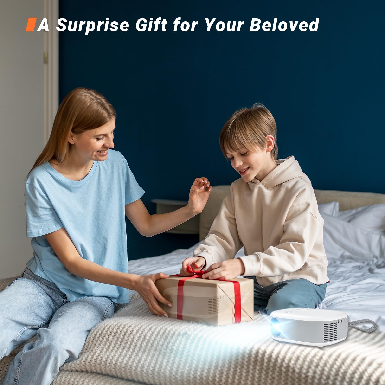Mini-Beamer auf Bettdecke mit Projektion, daneben liegendes Geschenkpaket
