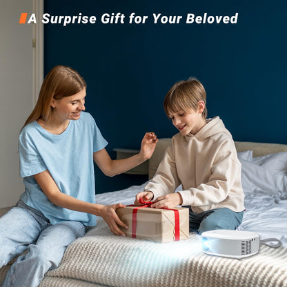 Mini-Beamer auf Bettdecke mit Projektion, daneben liegendes Geschenkpaket