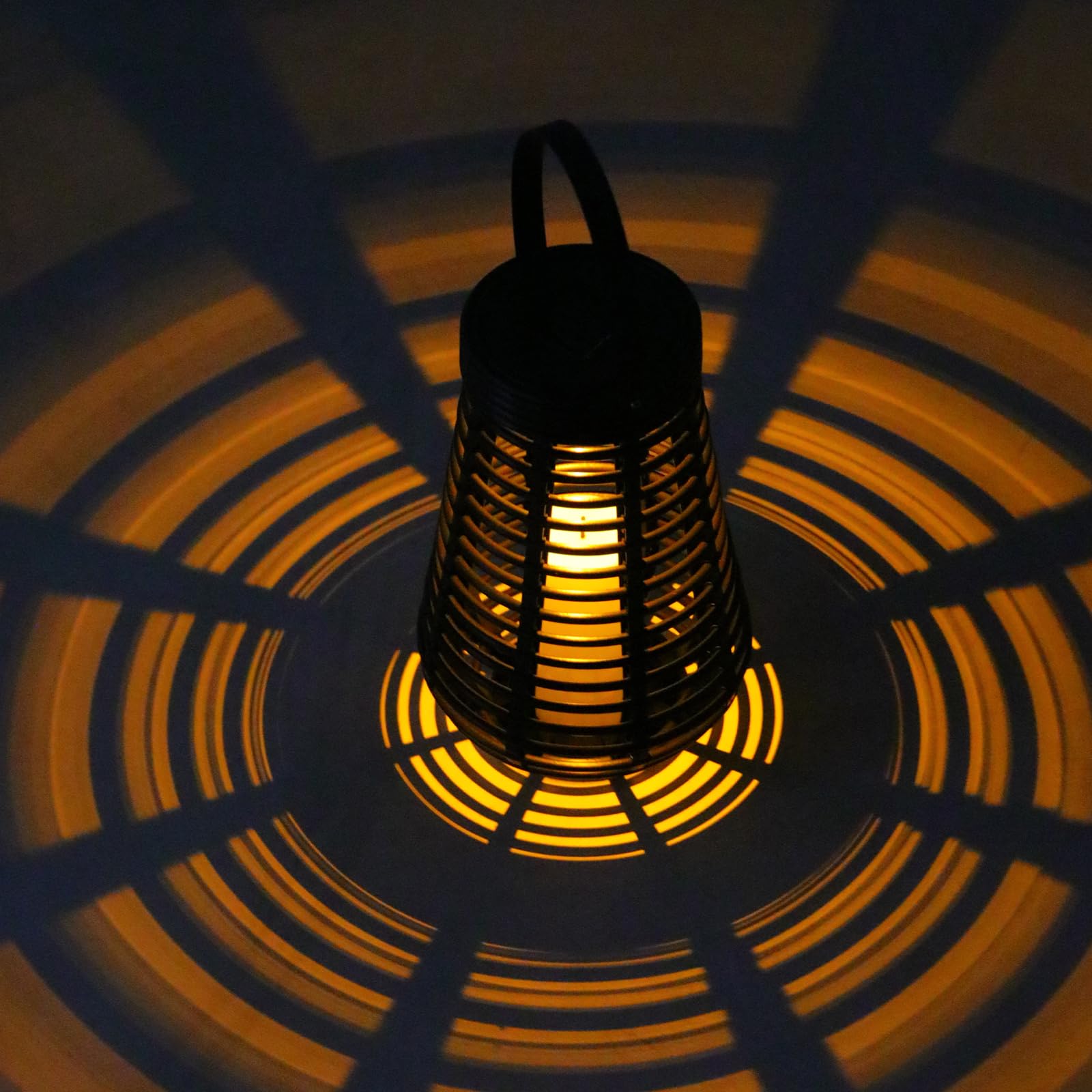 Schwarze Solarlaterne mit warmweiß leuchtendem Innenlicht und Rattan-Gitter, frontal