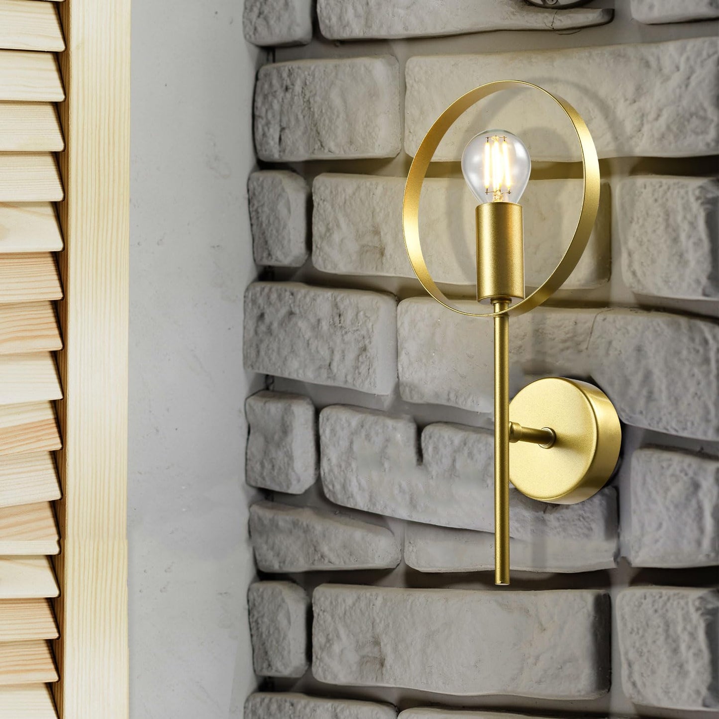 Goldene Wandleuchte mit rundem Metallring an Steinwand, E14-Fassung