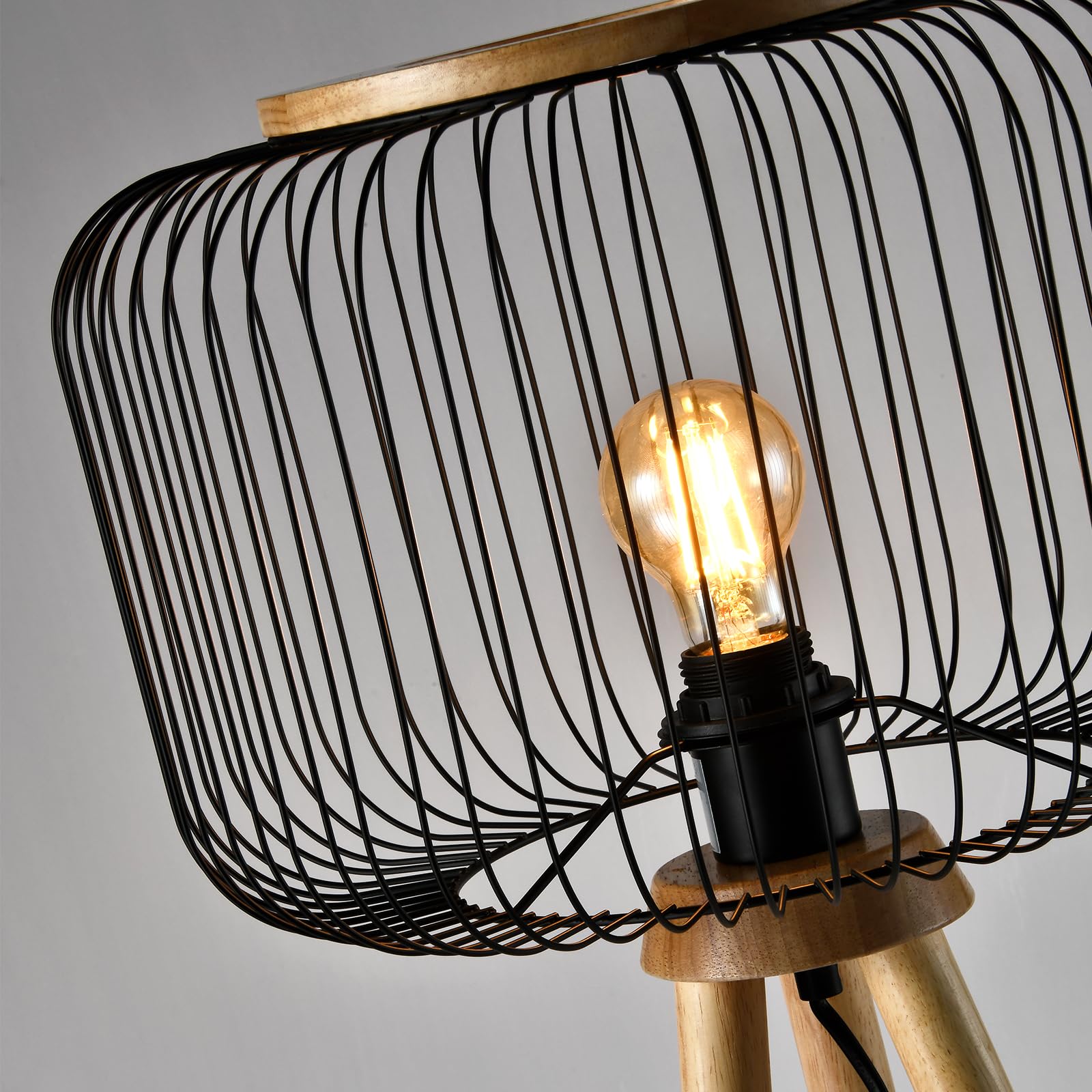Stehlampe mit schwarzem Drahtschirm und goldfarbenem Stativ, Glühbirne im Fokus