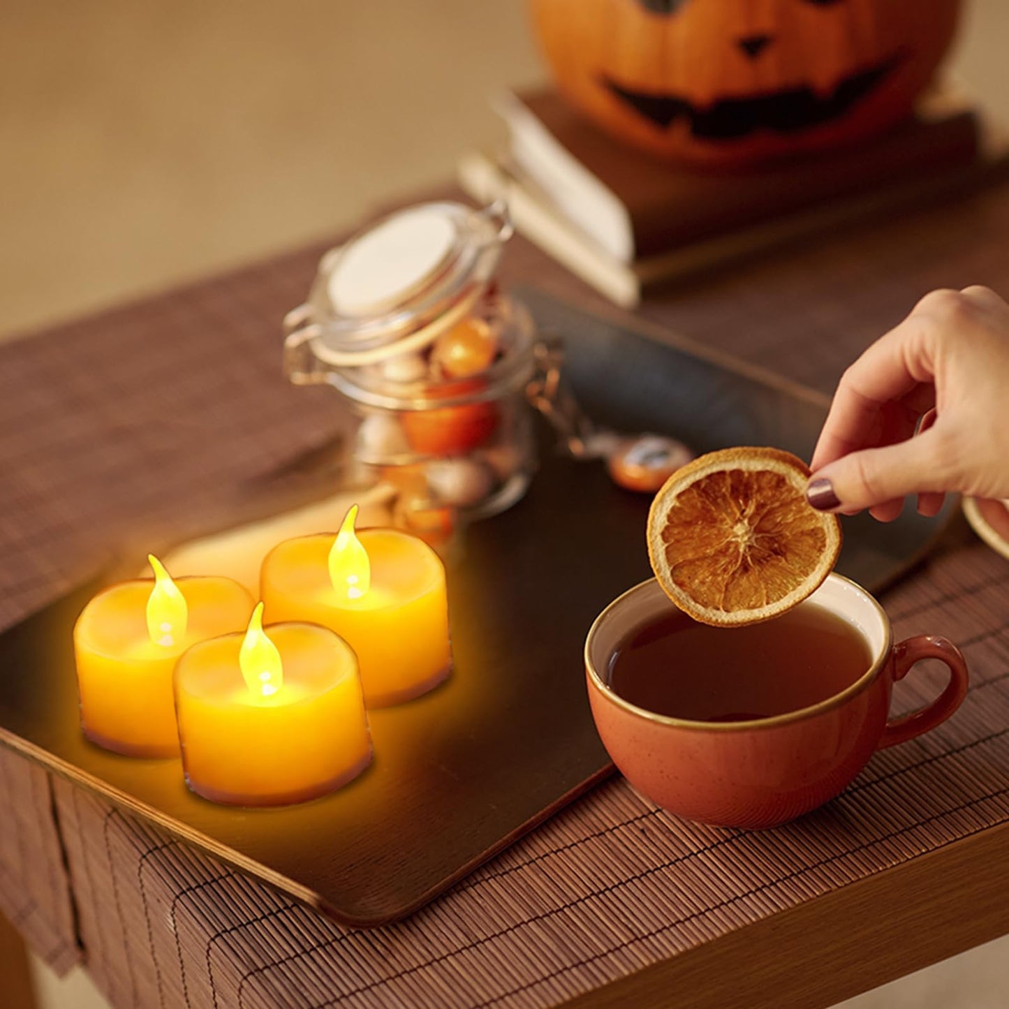 LED-Teelichter auf Tablett neben Tasse, warmes Flackern der gelben Kerzen