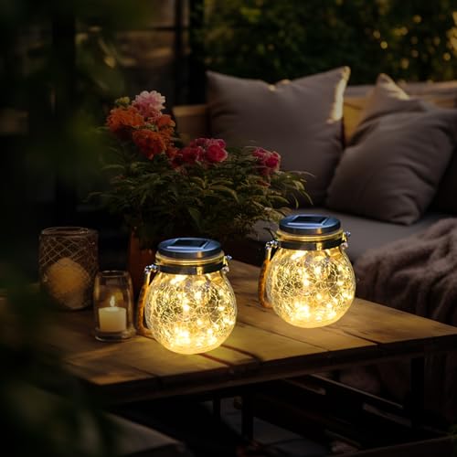 Solar-Laternen mit goldener Glaskugel und warmem Licht auf einer Gartentischplatte
