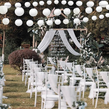 Hochzeitsdekoration mit weißen Papier-Laternen an einer Lichterkette über Stühlen