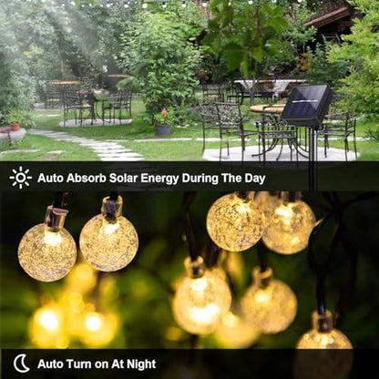 Solar-Lichterkette mit goldenen Kugeln, Solarpanel und Leuchten bei Nacht